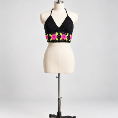 Front view of a black crochet halter crop top with pink flower motifs and bright green leaf details along the lower band