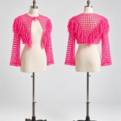Front and back of a hot pink cropped mesh crochet cardigan with long sleeves, neckline ties and shoulder and back fringe