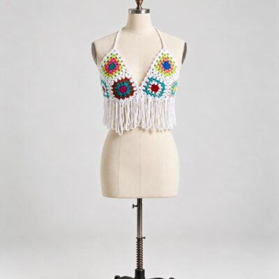 Front view of an ivory crochet halter top with bright multicolor floral motifs, a deep V neckline and long looped fringe