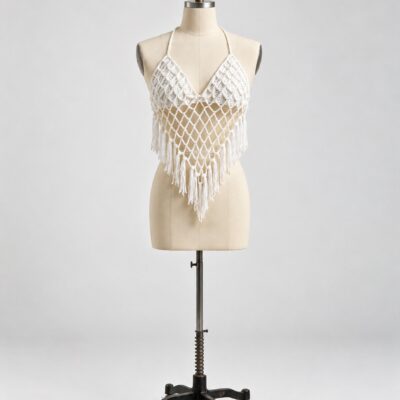 Front view of an ivory crochet halter top with textured upper panels, diamond mesh pointed front and fringe edging